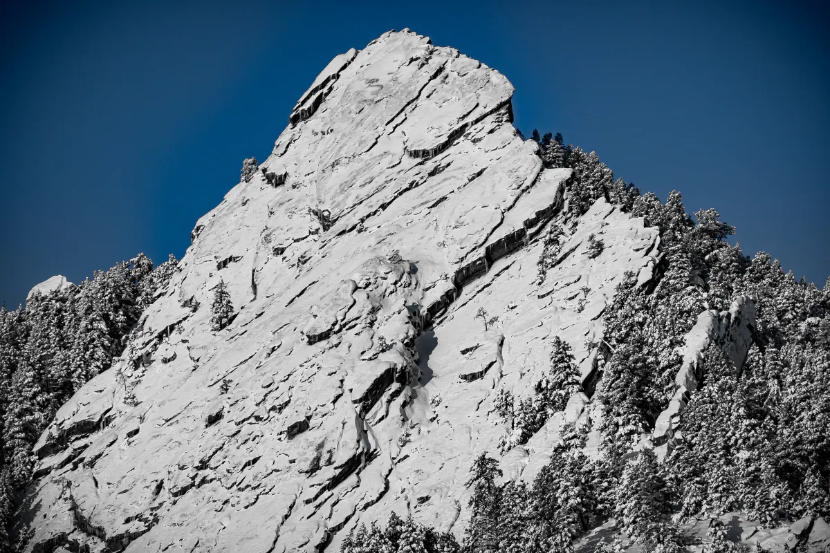 Snow-covered rock face rising against a deep blue sky
